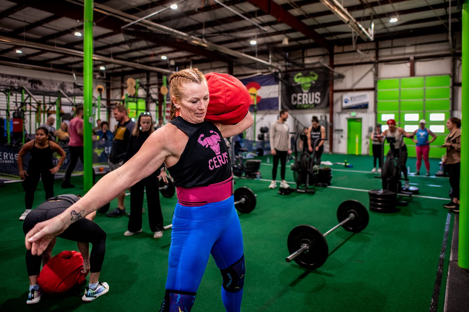 Cerus Fitness member carrying a sandbag during a coached strength training session