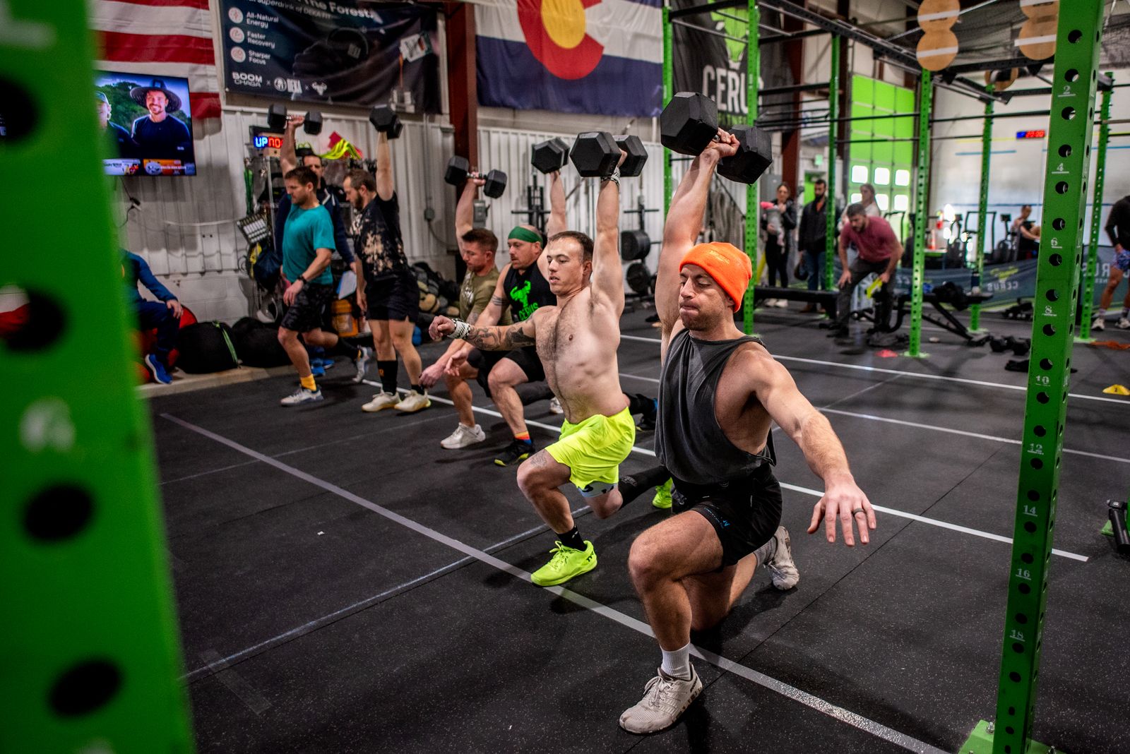 Cerus Fitness members performing overhead dumbbell lunges during a coached HYROX training session